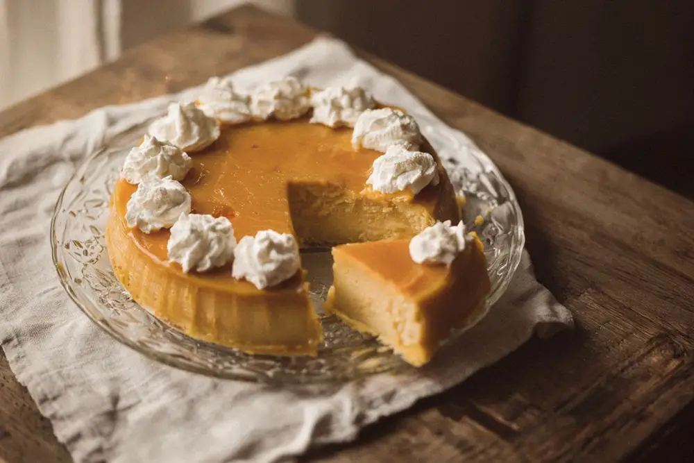 A golden apricot cream unmoulded onto a glass plate, decorated with whipped cream and served chilled