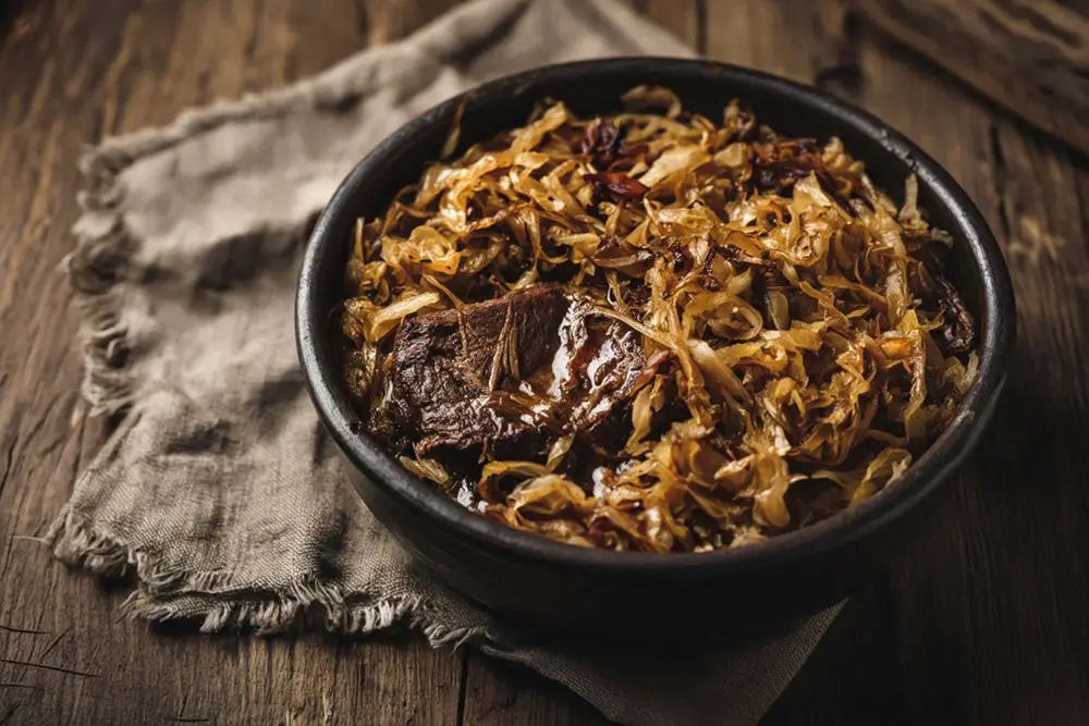 Slow-braised sauerkraut with pastrma and beef in a rustic earthenware pot, rich and deeply coloured